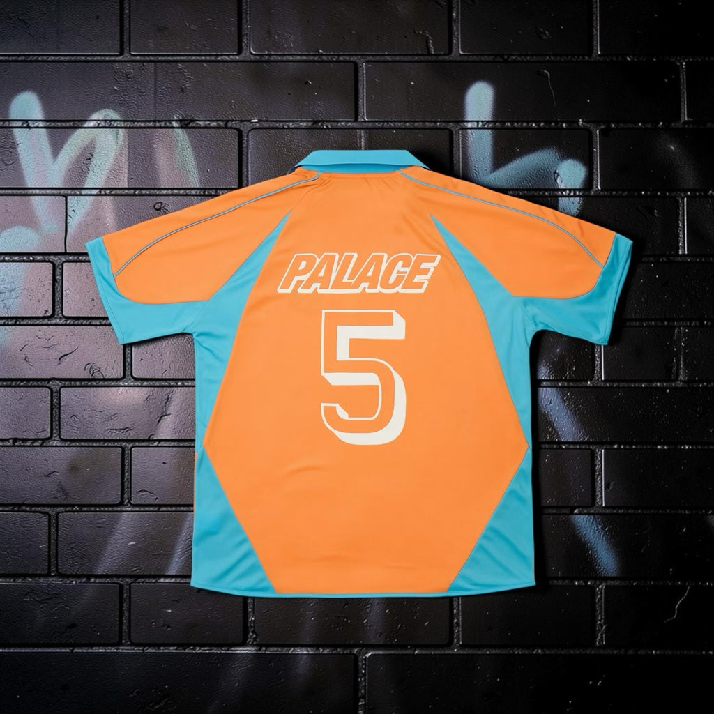 Aurora Fashion Palace orange and turquoise football-style jersey with number 5 on the back against a brick wall
